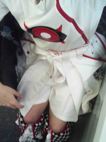 My outfit, taken sitting on the train. White shirt with a red and black eye on it and red zip, as well as matching white shorts and leg warmers wth red trim and checkerboard pattern accent spots.